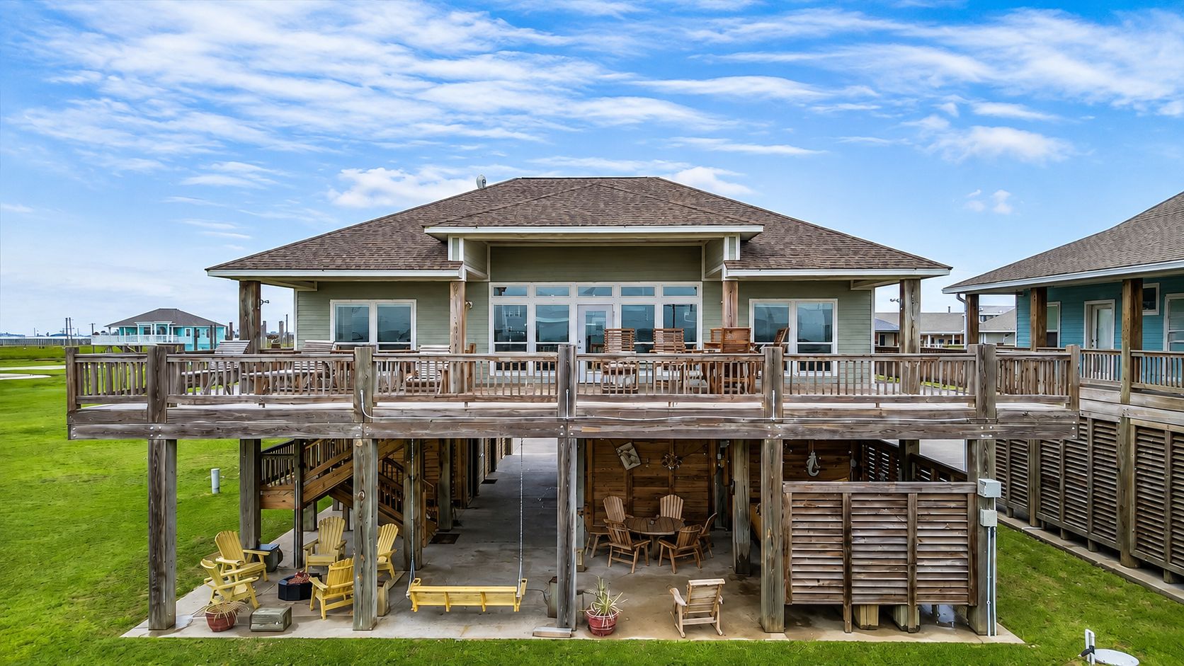 A two-story house with a deck, outdoor seating, and a covered area.
