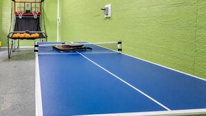 A blue ping pong table with a net in an indoor setting. - Crystal Beach Views | 4BR | Sleeps 11 | Hot Tub (Port Bolivar)