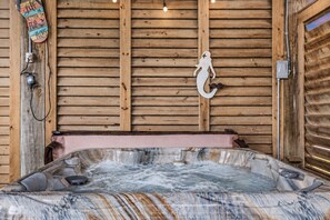 A hot tub with a wooden interior, a decorative wall with a mermaid figure, and a wooden ceiling with horizontal planks. - Crystal Beach Views | 4BR | Sleeps 11 | Hot Tub (Port Bolivar)