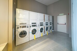 Filera de rentadores apilades en una habitació amb una porta amb la inscripció 'SALIDA' i un sòl de rajola.