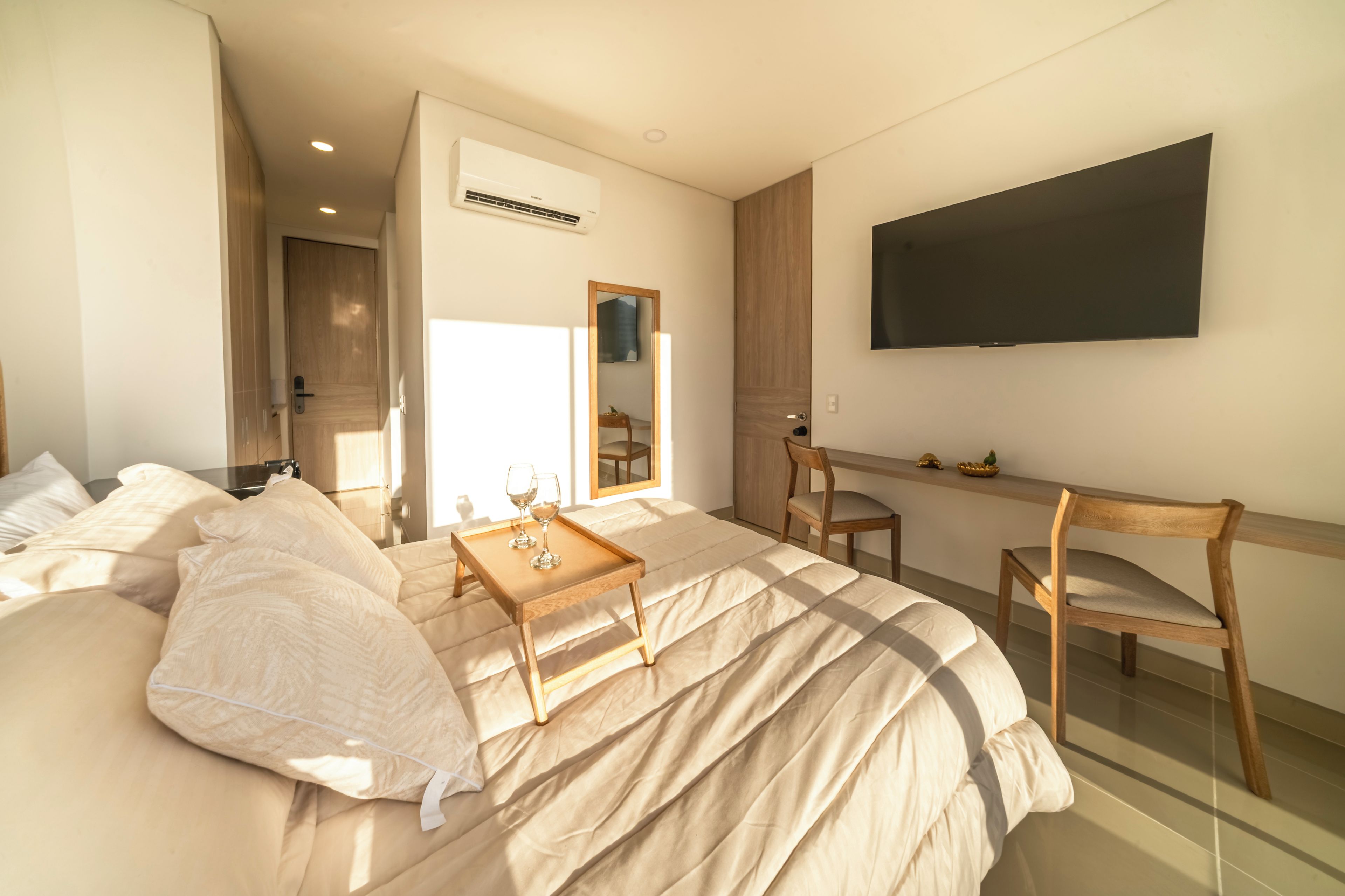 A modern bedroom with a bed, bedside tables, a TV, and a mirror.