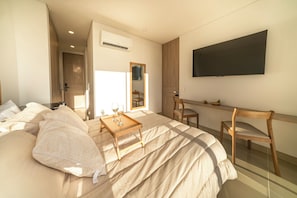 Une chambre à coucher moderne avec un lit, des tables de chevet, une télévision et un miroir.
