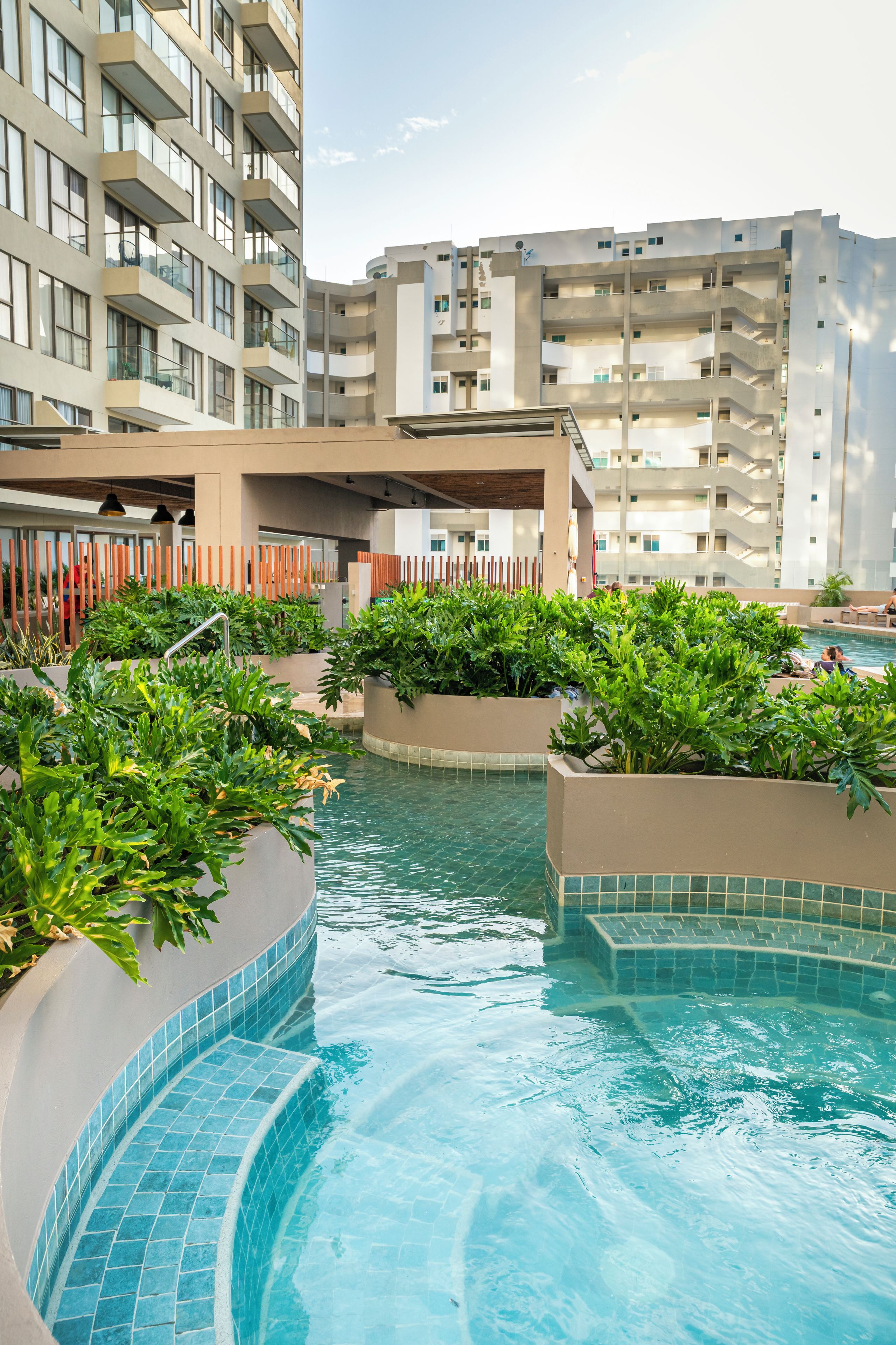 A swimming pool area with multiple levels of balconies and a view of adjacent buildings.