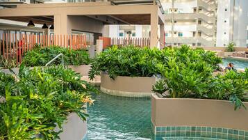 A swimming pool area with multiple levels of balconies and a view of adjacent buildings.