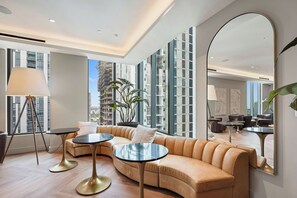 A modern living room with a curved sofa, two round tables, a floor lamp, and a large mirror reflecting the room. - 501 First Chic Studio Balcony Downtown Miami (Miami)
