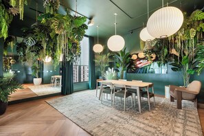 Ein modernes Interieur mit Essbereich, hängenden Pflanzen und einem großen Fenster.