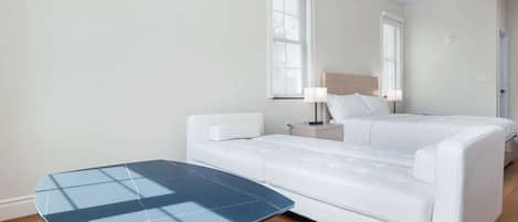 A hotel room with a bed, a bedside table, a lamp, a ceiling fan, and a small table.