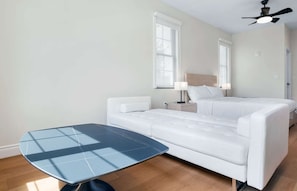 A modern hotel room with a bed, a bedside table, a lamp, and a small table with a blue top.