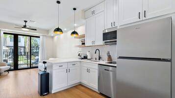 A modern kitchen with white cabinets, a stainless steel refrigerator, and pendant lighting.