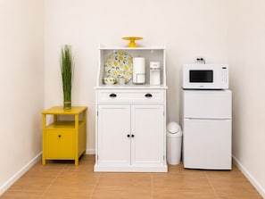 A kitchen with a white cabinet, a yellow side table, a microwave, and a trash can. -     Charming Island Studio Relax & Unwind in Anguilla (The Valley)
