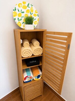 A wooden storage unit with towels and a makeup bag. -     Charming Island Studio Relax & Unwind in Anguilla (The Valley)