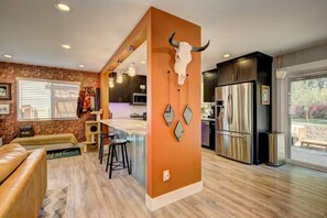 A modern kitchen with a central island, a stone accent wall, and a large bull skull decoration. - Hot Tub • Greenbelt• Fireplace • Telescope • Pets (Garden City)