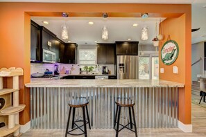 A modern kitchen with a central island, stainless steel appliances, and a cat tree. - Hot Tub • Greenbelt• Fireplace • Telescope • Pets (Garden City)