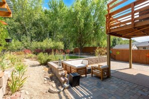 An outdoor patio with a hot tub, seating area, and a pergola structure. - Hot Tub • Greenbelt• Fireplace • Telescope • Pets (Garden City)