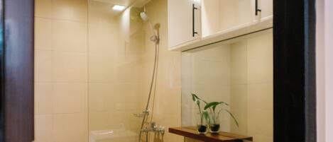 A modern bathroom with a glass-enclosed shower, a white toilet, and a sink with a mirror above.