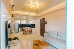 A modern living room with a sofa, a coffee table, and a dining area with chairs and a table. - Casa Honore Condominium (Iloilo)