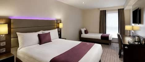 A hotel room with a large bed, a smaller bed, a desk, and a TV.