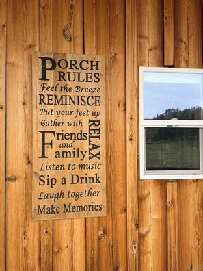A wooden wall with a sign listing 'Porch Rules' for relaxation and socializing.