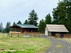 A rural property with a wooden barn, a metal shed, and a fenced paddock.