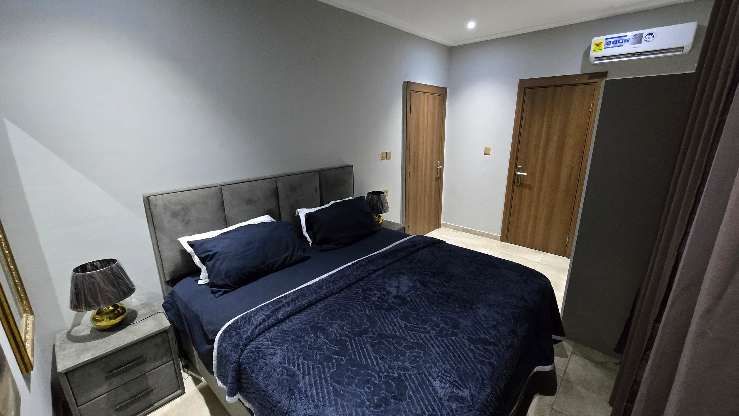 Un dormitorio con cama, mesitas de noche, lámpara y armario.