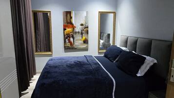 Une chambre à coucher avec un lit, des rideaux, un tableau et un miroir.