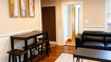 Una sala de estar con una mesa de madera oscura, un sofá de cuero negro y una alfombra estampada.