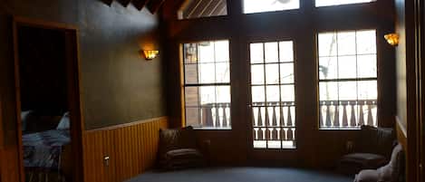 A room with a sloped ceiling, a ceiling fan, and a large window with a view of trees.