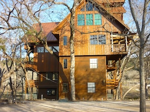 A multi-story wooden cabin with a balcony, surrounded by trees.