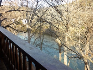 A view of a river with trees and a wooden railing.