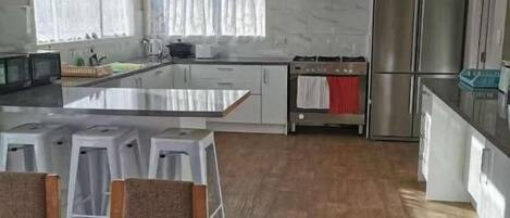 A modern kitchen with a central island, white cabinetry, and a stainless steel refrigerator.