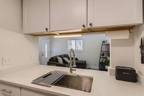 A kitchen with a stainless steel sink, a modern faucet, and a countertop. - Comfy 2-bedroom townhome in East Austin. Huge back yard! (Austin)