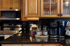 A kitchen with wooden cabinets, stainless steel appliances, and a coffee maker. - Stunning Views | Sauna | 4 Kings | Hot Tub | Golf (Gatlinburg)