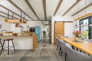 A modern kitchen with a central island, bar stools, and a dining area with a table and chairs. - Villa Sonnenschein (Istria - Svetvinčenat) (Svetvinčenat)