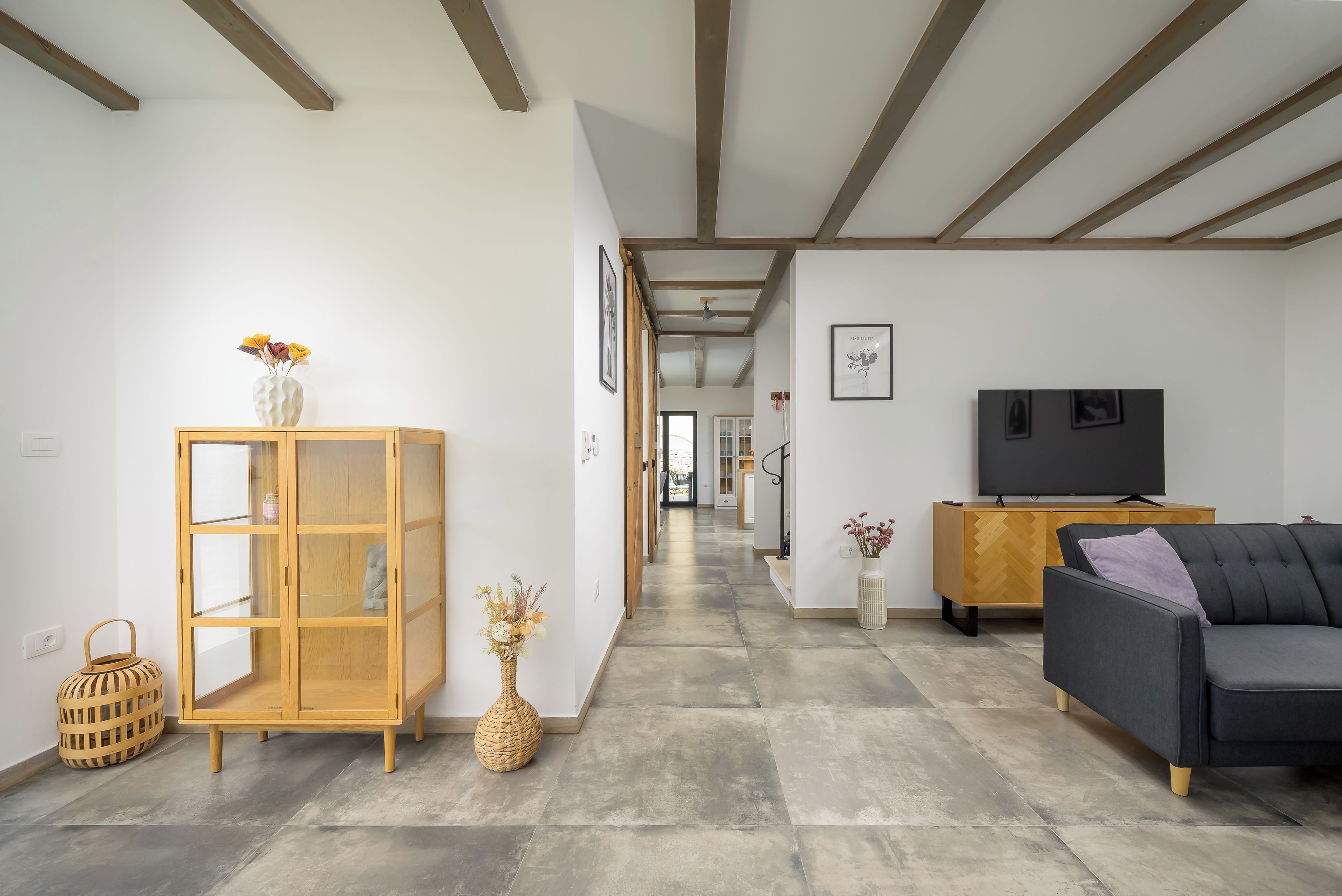 A modern living room with a sofa, TV, wooden cabinet, and decorative vases.