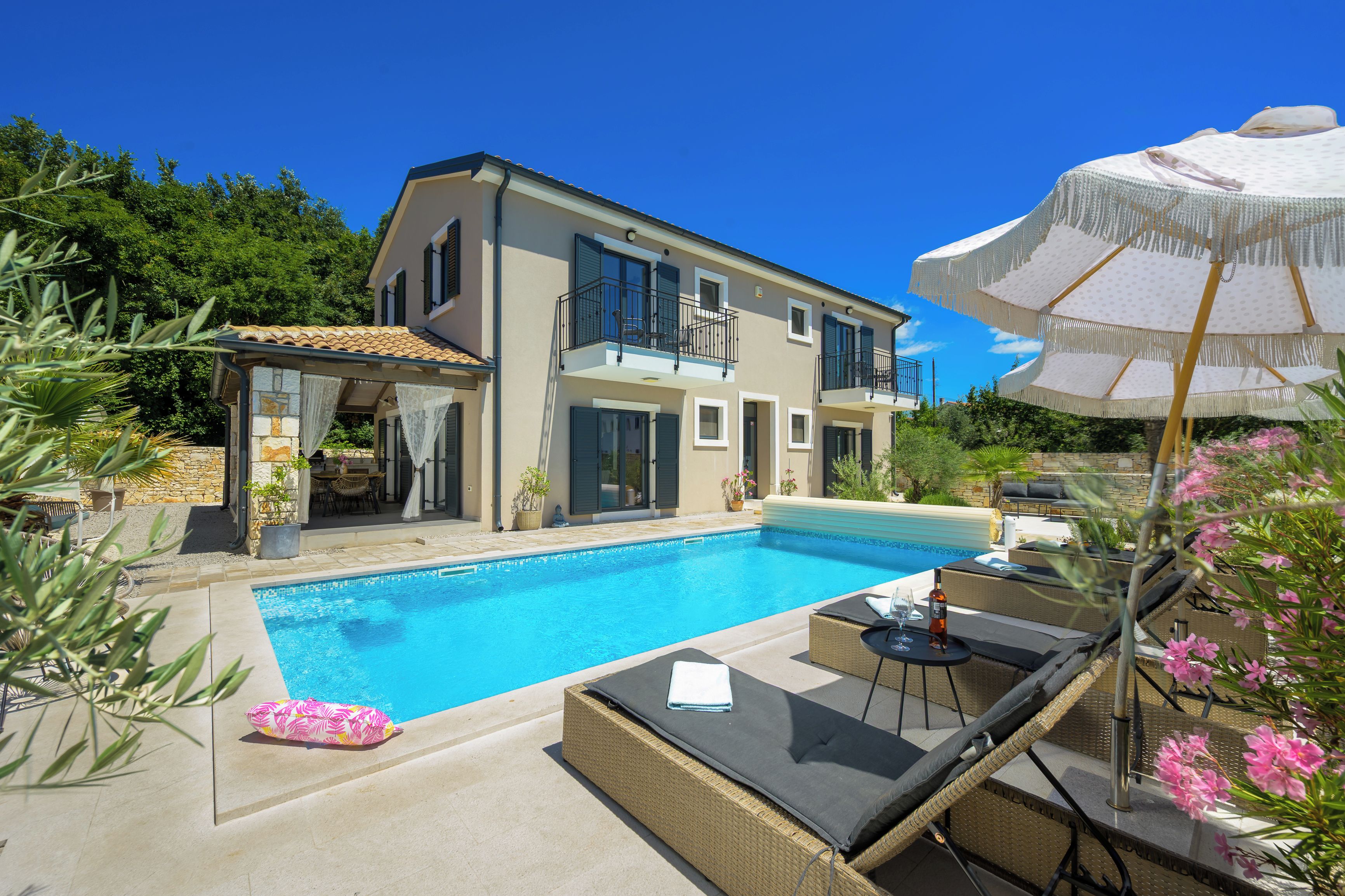 A two-story house with a swimming pool, outdoor furniture, and a pergola.