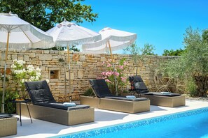 A poolside area with lounge chairs and umbrellas, a stone wall, and a clear blue sky. - Villa Sonnenschein (Istria - Svetvinčenat) (Svetvinčenat)