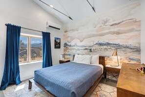 A bedroom with a bed, a desk, a chair, a window with curtains, and a wall mural. - Monthly Rental - Close to Town ~ Mountain Views ~ A/C (Salida)