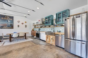 A modern kitchen with stainless steel appliances, teal cabinets, and a dining area with a white table and chairs. - Monthly Rental - Close to Town ~ Mountain Views ~ A/C (Salida)