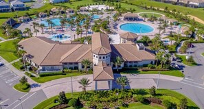 A resort with multiple swimming pools, palm trees, and a central building with a tower. - Luxury 9BR ChampionsGate Retreat Pool, Spa, Game Rooms & Resort Access (Davenport)