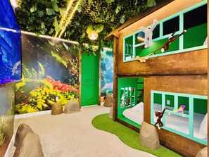 Ein Kinderspielbereich mit Wandmalerei, grüner Tür und Klettergerüsten.