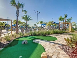 A golf putting green with palm trees and lounge chairs. - Luxury 9BR ChampionsGate Retreat Pool, Spa, Game Rooms & Resort Access (Davenport)