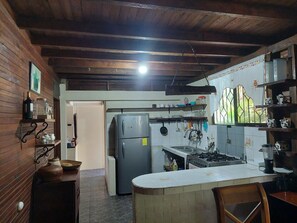 A kitchen with wooden beams, a refrigerator, a stove, and various kitchen utensils.
