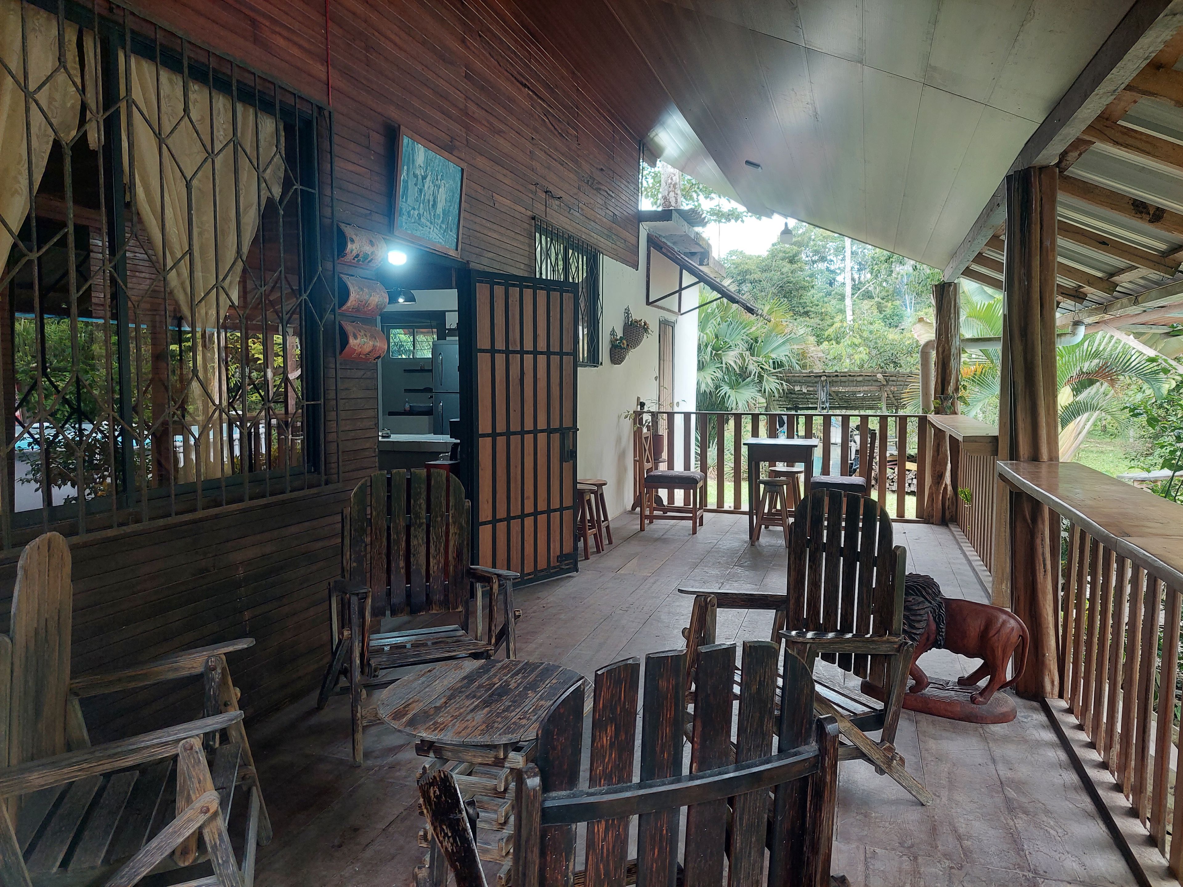 Une terrasse en bois, agrémentée de meubles rustiques, notamment une table ronde et des chaises, ainsi qu’un banc en bois.