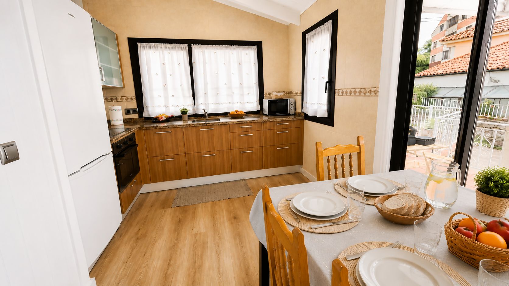 Una cocina compacta con armarios de madera, un microondas y un comedor con una mesa preparada para dos.