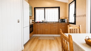 A compact kitchen with wooden cabinets, a microwave, and a sink.