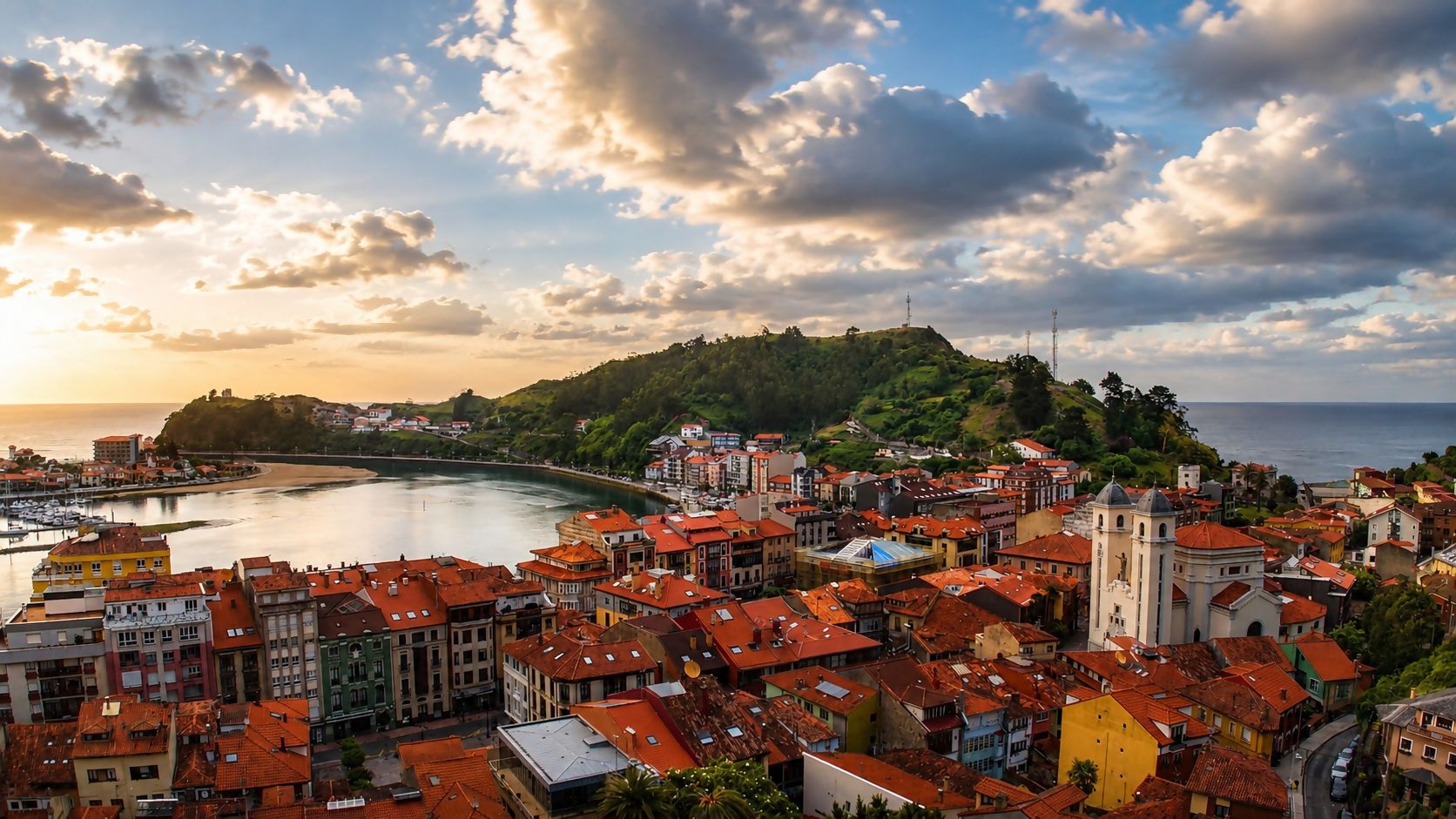 A coastal town with a prominent church and a hill with a tower.