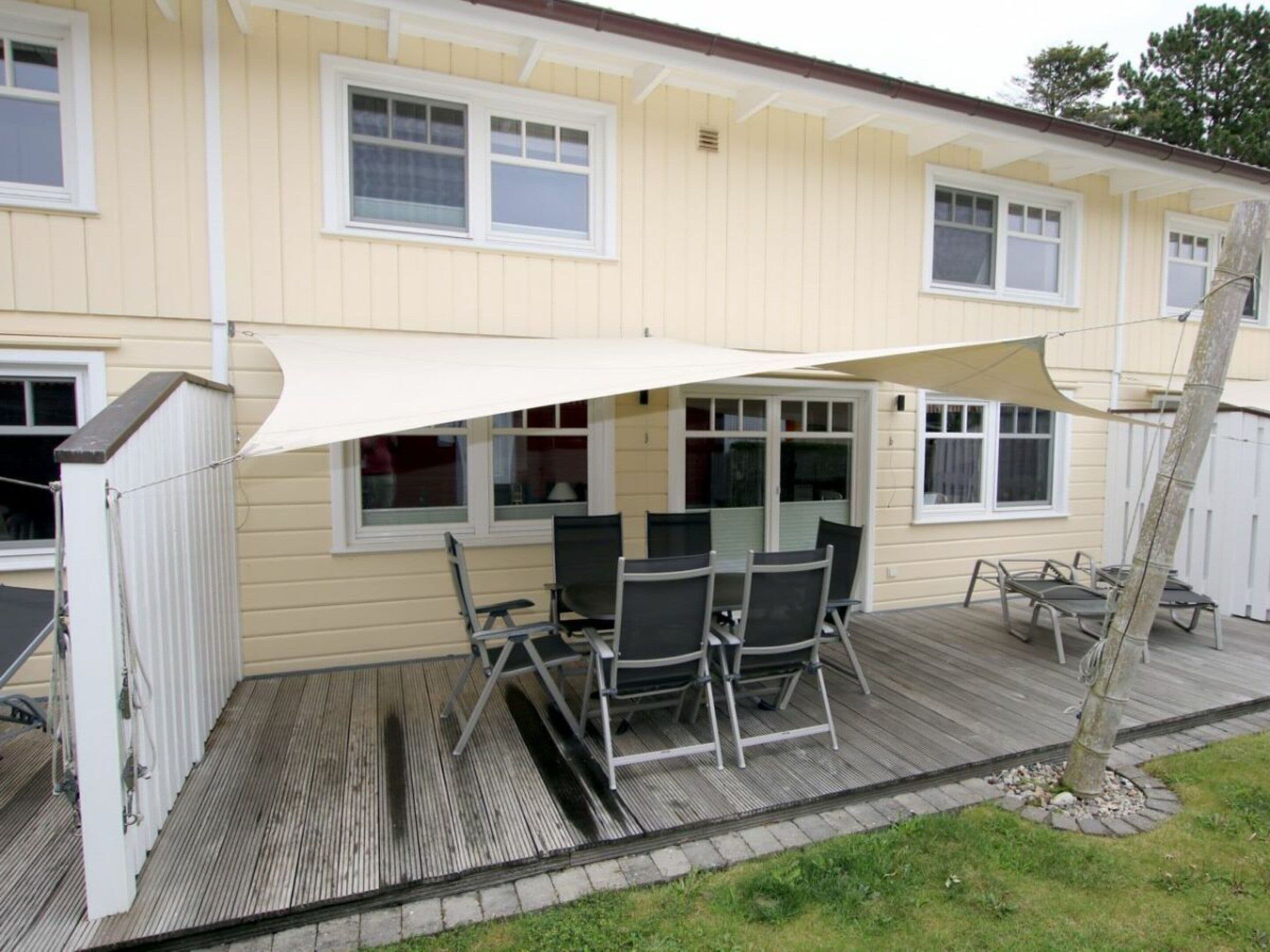 Una casa con un patio cubierto que incluye una mesa y sillas.