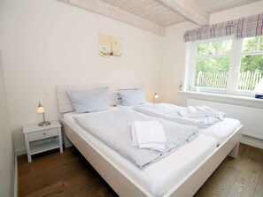 Ein Schlafzimmer mit einem großen Bett, Nachttischen, einem Fenster mit Vorhängen und einem Bild an der Wand.