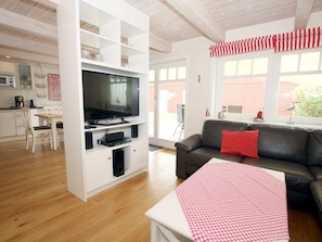 Ein Wohnzimmer mit Fernseher, einer Couch und einem Essbereich mit Tisch und Stühlen.
