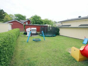 Ein Garten mit Trampolin, Schaukel und Rutsche.